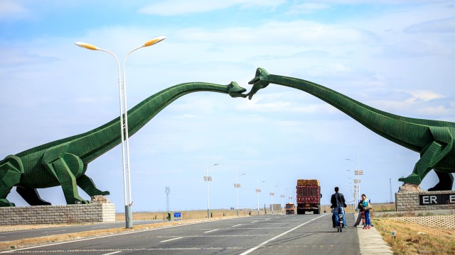 A couple of dinasours doing french kiss in the middle of the road...